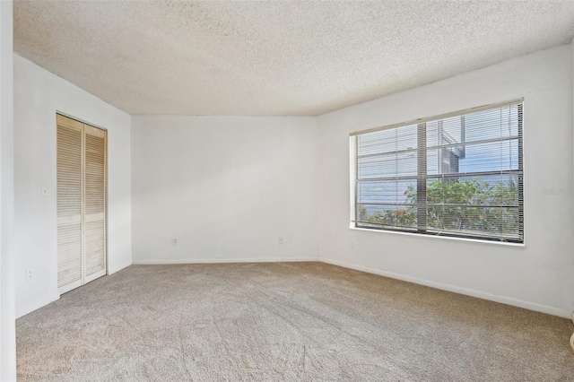 empty room with light carpet and a textured ceiling