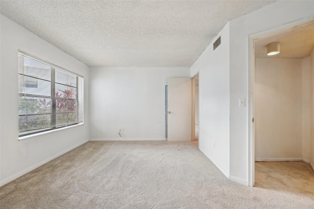 empty room with a textured ceiling and light colored carpet