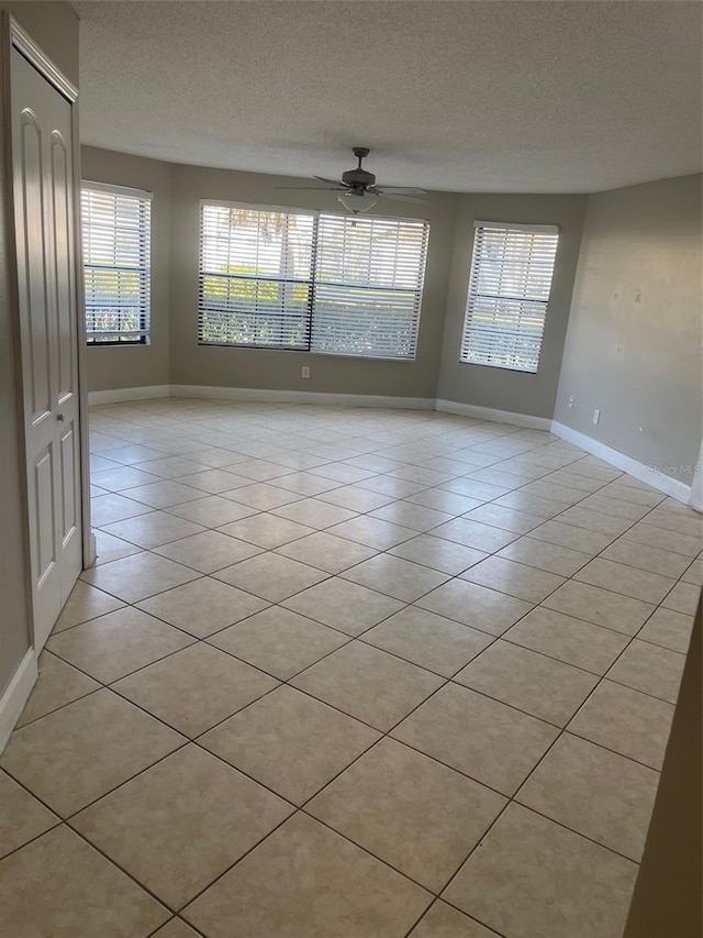 empty room with light tile patterned floors, a textured ceiling, and plenty of natural light