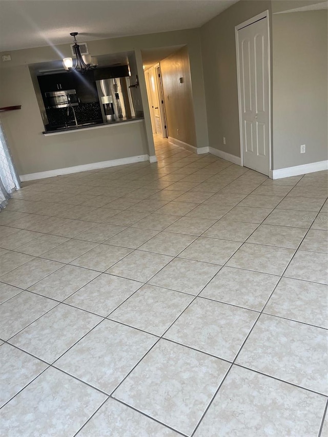 unfurnished living room with a chandelier, tile patterned flooring, visible vents, and baseboards