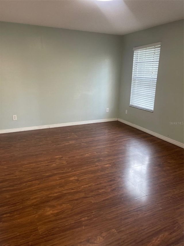 unfurnished room featuring dark wood-style flooring and baseboards