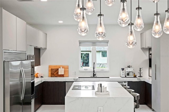 kitchen featuring sink, white cabinets, stainless steel appliances, dark brown cabinetry, and light stone countertops