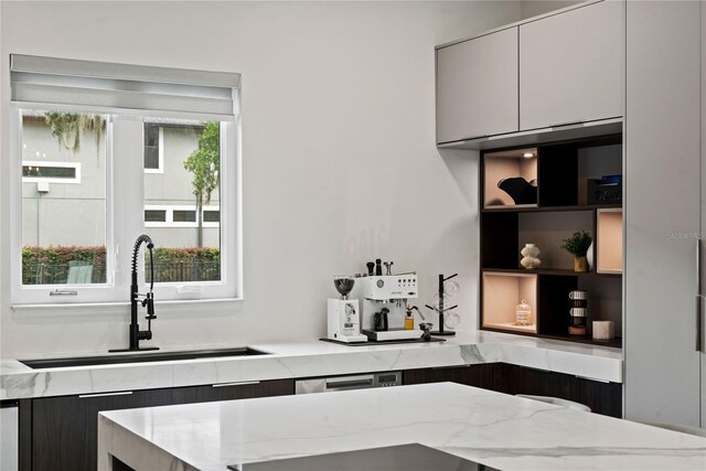 kitchen featuring a center island, light stone countertops, sink, and white cabinets