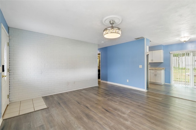 spare room featuring brick wall and hardwood / wood-style floors