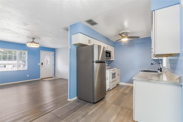 kitchen featuring stainless steel appliances, light hardwood / wood-style floors, white cabinets, ceiling fan, and sink