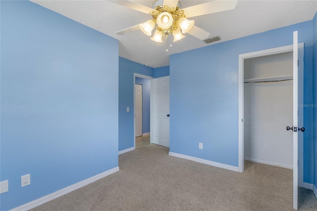 unfurnished bedroom featuring light colored carpet, ceiling fan, a textured ceiling, and a closet