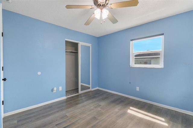 unfurnished bedroom with a closet, ceiling fan, a textured ceiling, and dark hardwood / wood-style floors