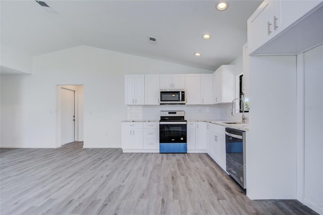 kitchen with white cabinets, lofted ceiling, sink, stainless steel appliances, and light wood-type flooring