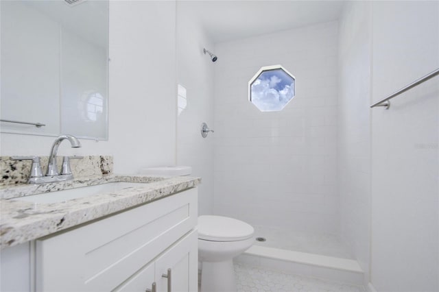 bathroom with a tile shower, vanity, and toilet