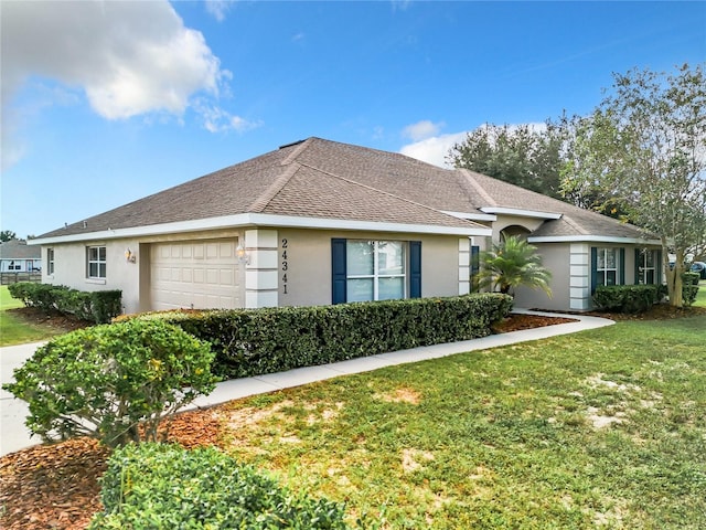 ranch-style home with an attached garage, roof with shingles, a front yard, and stucco siding