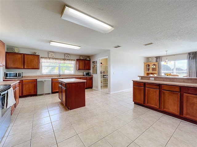 kitchen featuring stainless steel appliances, visible vents, a sink, a center island, and a textured ceiling