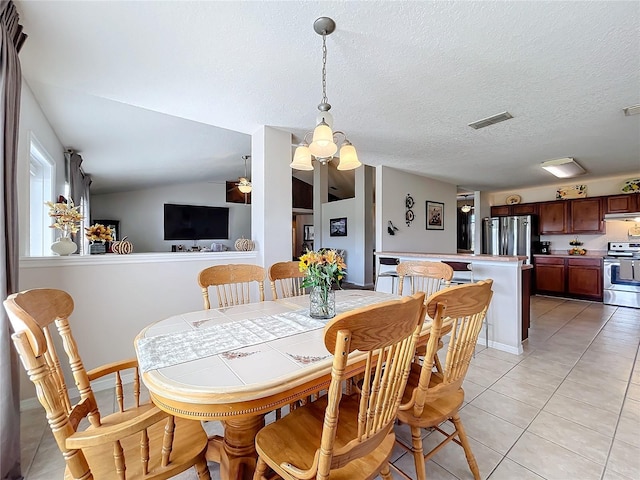 tiled dining area featuring a textured ceiling, vaulted ceiling, and ceiling fan