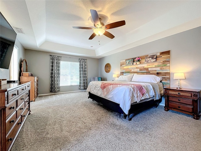 carpeted bedroom featuring wood walls, ceiling fan, and a raised ceiling