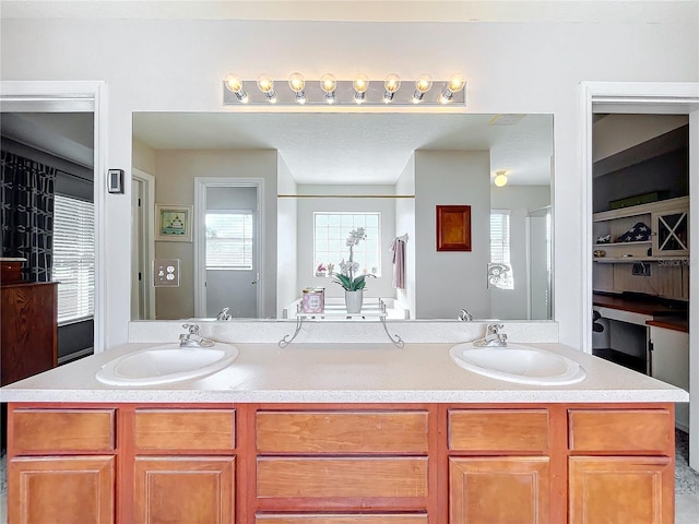 bathroom with double vanity, a shower with shower door, and a sink