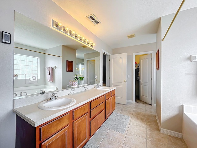 full bathroom with double vanity, visible vents, a garden tub, and a sink