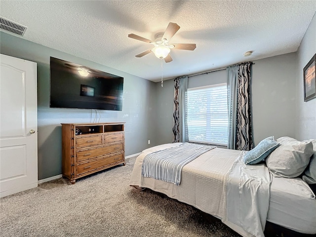 bedroom with ceiling fan, carpet floors, and a textured ceiling