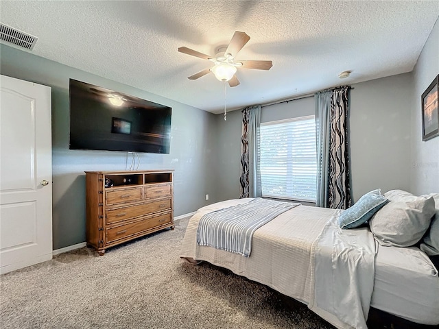 carpeted bedroom with visible vents, baseboards, a textured ceiling, and ceiling fan