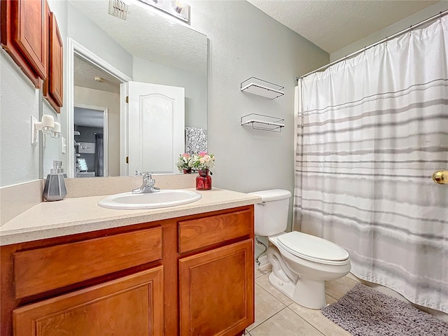 bathroom with toilet, vanity, tile patterned floors, and a textured ceiling