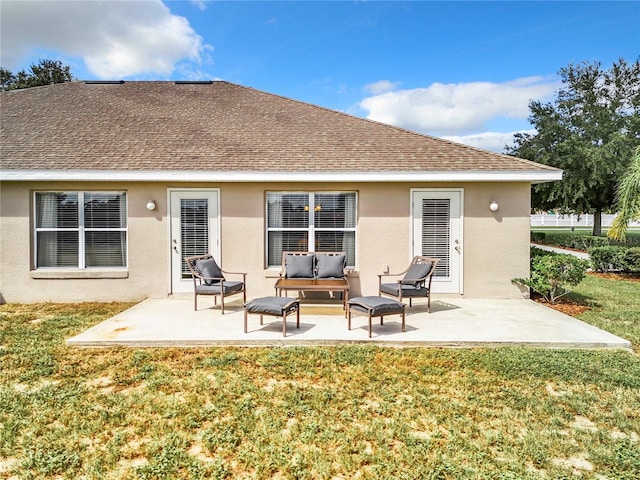 rear view of house with stucco siding, roof with shingles, and a patio