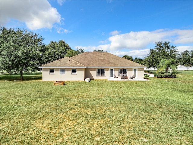 back of property with a yard, a patio area, and stucco siding