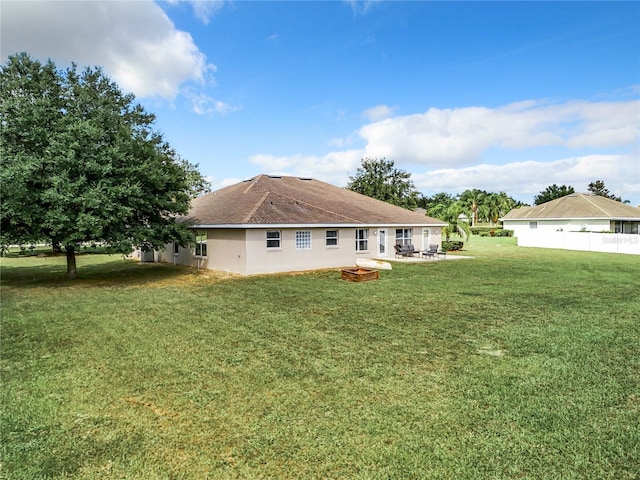 back of property with a fire pit, a yard, and a patio