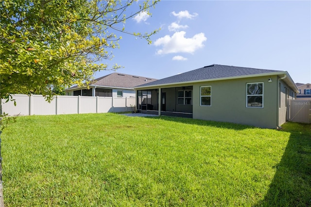 rear view of property featuring a lawn and a sunroom