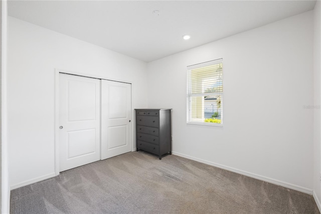 unfurnished bedroom with a closet and light colored carpet