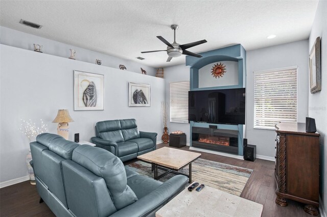 living room with ceiling fan, a textured ceiling, and dark hardwood / wood-style flooring