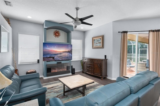 living room featuring a textured ceiling, dark wood-type flooring, and ceiling fan