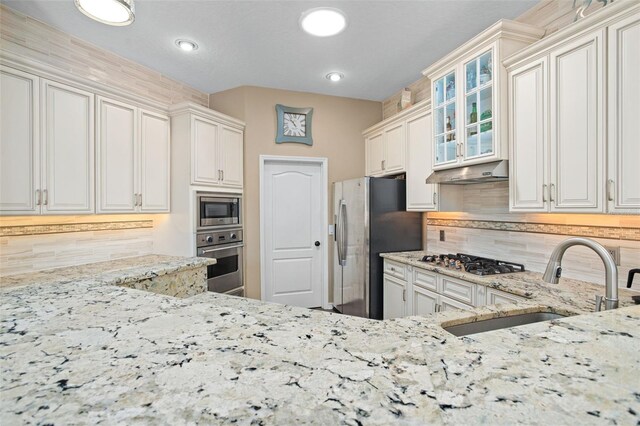 kitchen featuring stainless steel appliances, white cabinets, tasteful backsplash, and sink