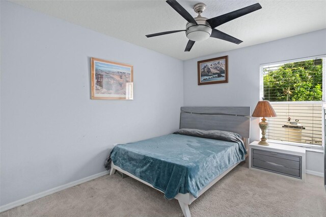 carpeted bedroom featuring ceiling fan and a textured ceiling