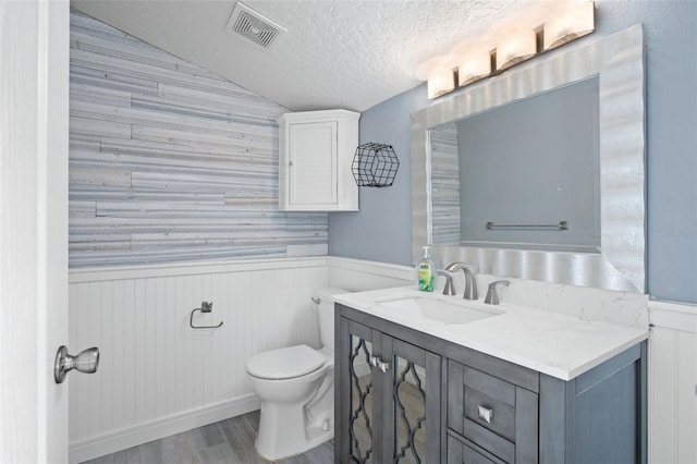 bathroom featuring vaulted ceiling, vanity, a textured ceiling, toilet, and hardwood / wood-style floors