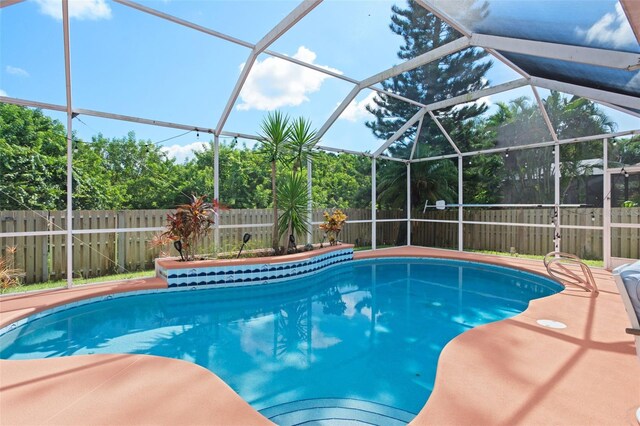 view of swimming pool featuring glass enclosure and a patio