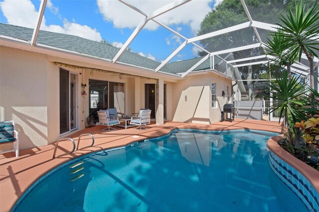 view of swimming pool featuring ceiling fan, a patio, and a lanai