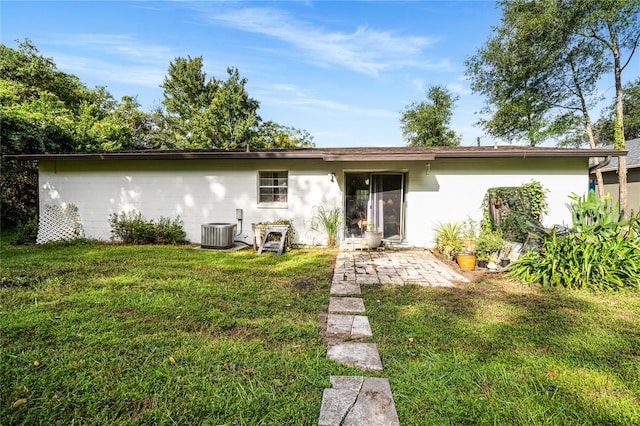 back of property with central AC unit and a lawn