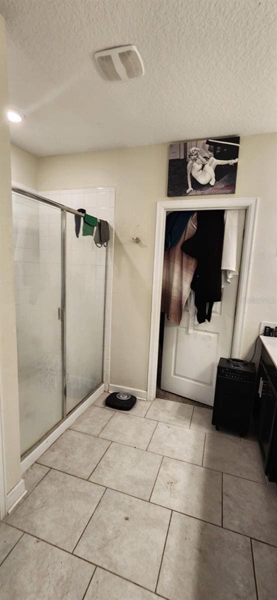 bathroom featuring walk in shower, vanity, tile patterned flooring, and a textured ceiling