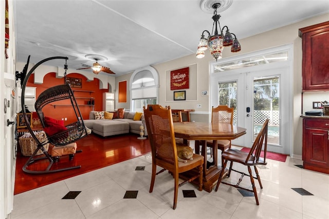 dining area featuring french doors, light tile patterned flooring, and ceiling fan with notable chandelier