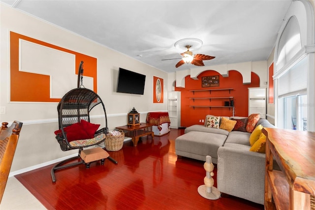 living area featuring arched walkways, baseboards, ceiling fan, and wood finished floors