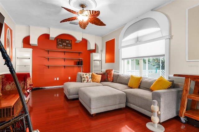 living room with arched walkways, crown molding, wood finished floors, and ceiling fan