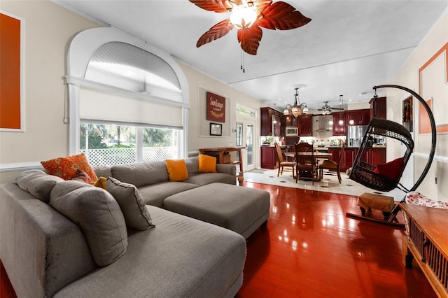 living area featuring ceiling fan with notable chandelier and dark wood-type flooring
