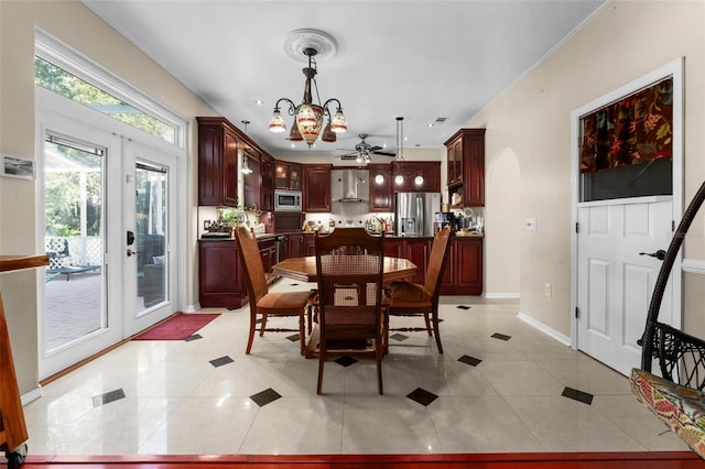 tiled dining space featuring ceiling fan with notable chandelier and french doors