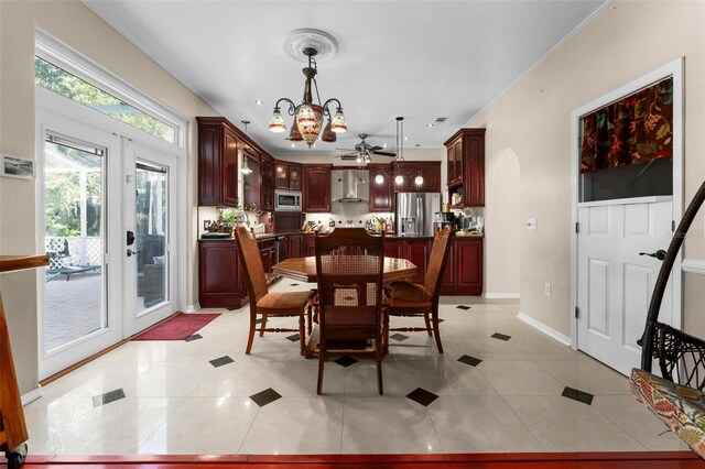 dining room with arched walkways, light tile patterned floors, baseboards, and ceiling fan with notable chandelier