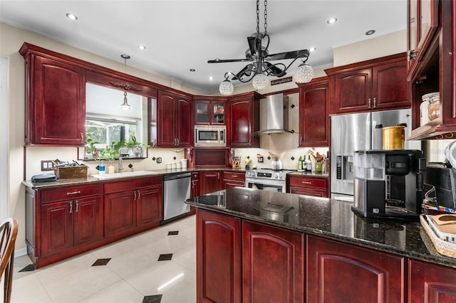 kitchen with a sink, wall chimney exhaust hood, dark brown cabinets, and appliances with stainless steel finishes