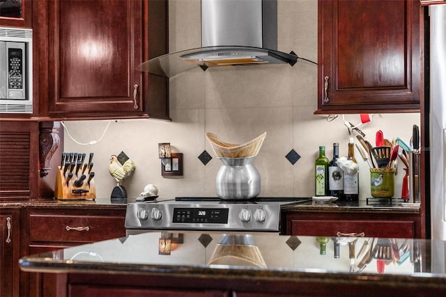 kitchen with dark countertops, wall chimney exhaust hood, and stainless steel microwave