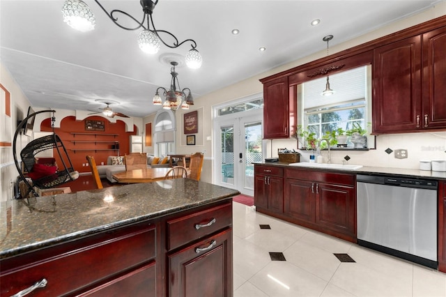kitchen featuring reddish brown cabinets, a sink, ceiling fan with notable chandelier, pendant lighting, and stainless steel dishwasher