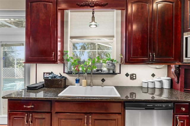 kitchen featuring dark stone countertops, appliances with stainless steel finishes, hanging light fixtures, and sink