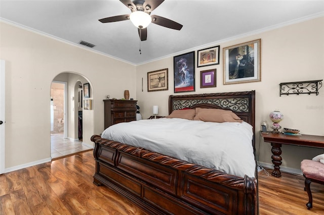 bedroom featuring wood-type flooring, ceiling fan, connected bathroom, and crown molding