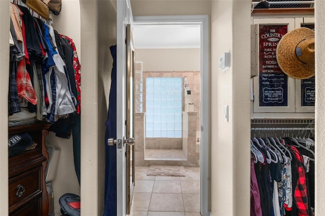 bathroom with tile patterned floors and a walk in closet