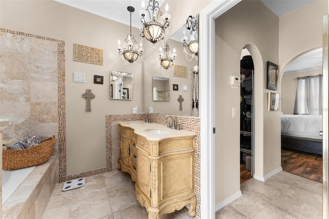 bathroom featuring tile patterned floors, a walk in closet, baseboards, and vanity