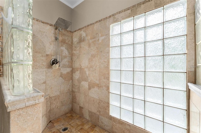 bathroom featuring a healthy amount of sunlight, crown molding, and tiled shower